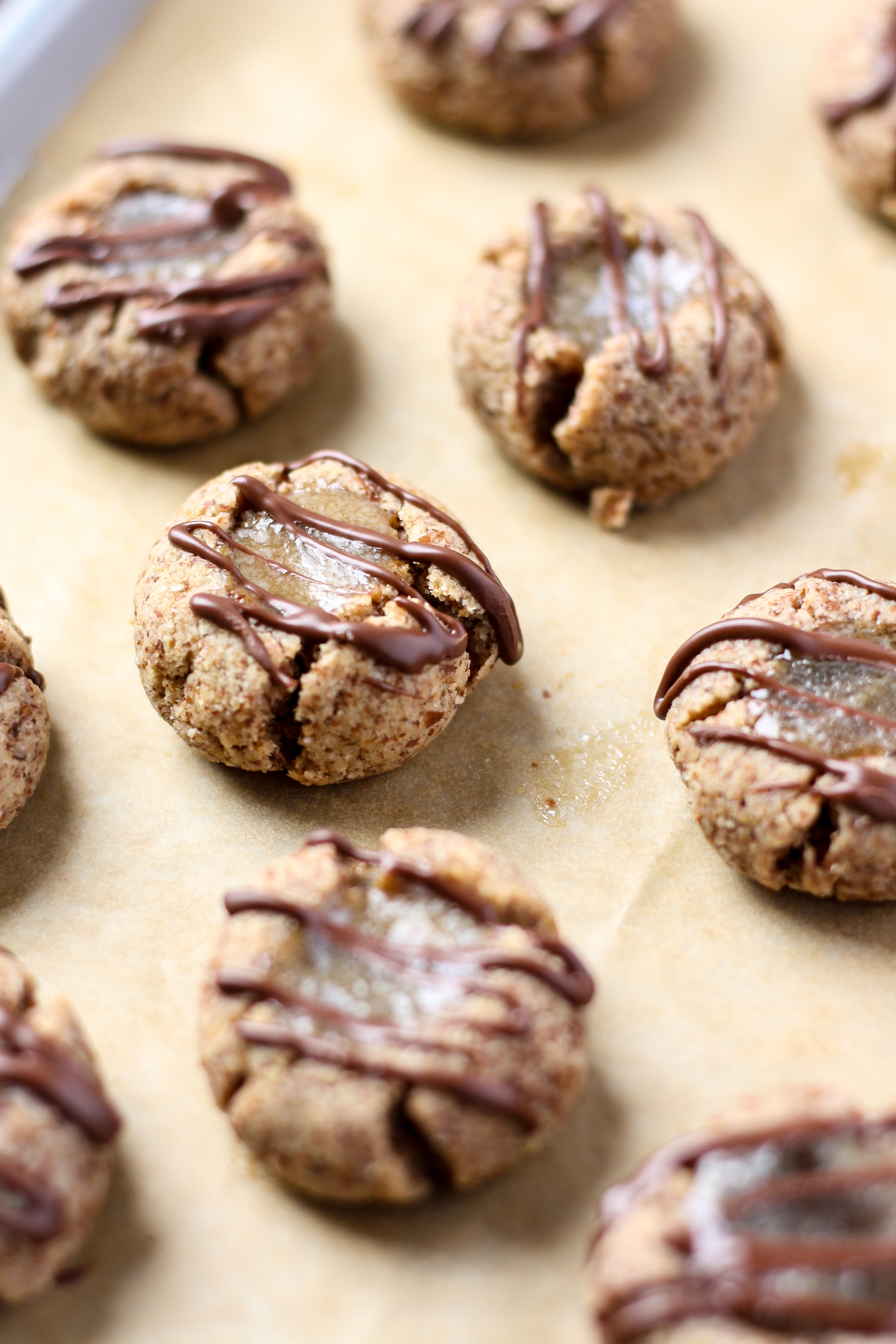 Cute, bite-sized, grain-free thumbprints with salted caramel centers and chocolate drizzle, these cookies are the perfect treat for your paleo peeps.