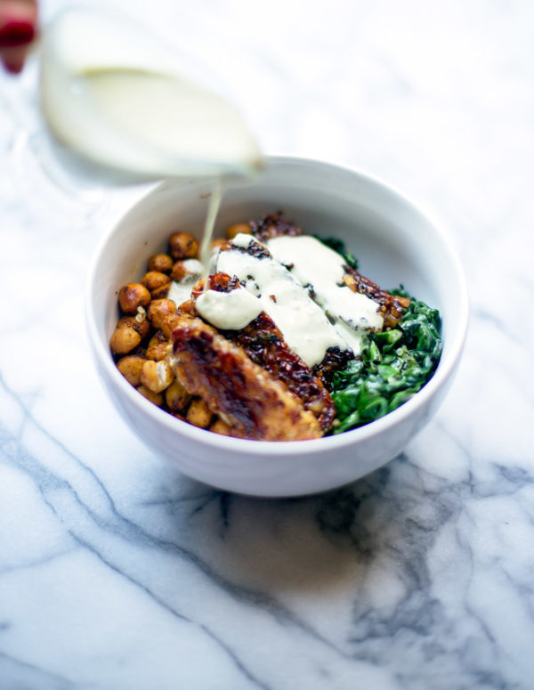 This hearty, satisfying bowl is packed with quinoa, kale, blackened tempeh, spiced chickpeas and is topped with a garlicky tahini sauce.
